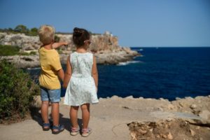 image for my weekly outlook for august featuring two children standing near a cliff watching on ocean at daytime